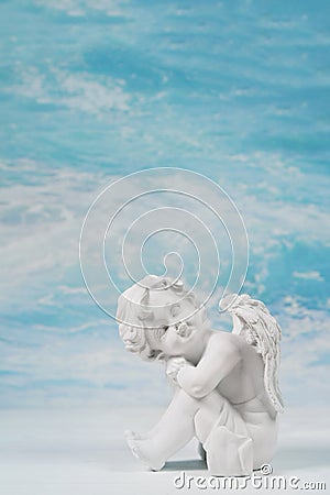 Dreaming or sad white angel on blue heaven background for a condolence card. Stock Photo