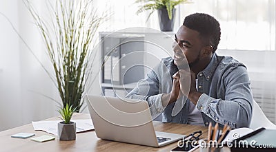 Portrait of pensive black employee sitting at workplace in office Stock Photo