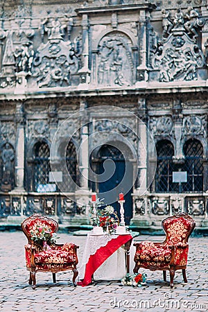 Dreamlike red and white colored table with luxurious armchairs with the old baroque architecture on background Stock Photo