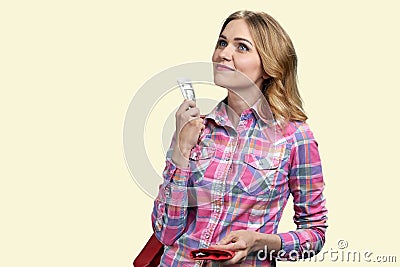 Dreamy caucasian girl holding dollar bills and thinking about shopping. Stock Photo