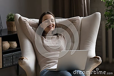 Dreamy cheerful millennial girl using laptop on lap Stock Photo
