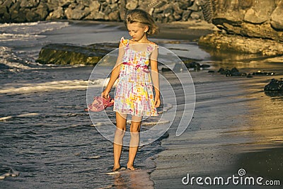 A dreamy girl blonde in a beautiful dress walks along the shore, soft focus Stock Photo