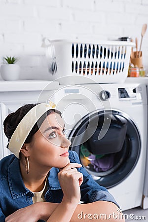 Dreamy housewife sitting near blurred washing Stock Photo