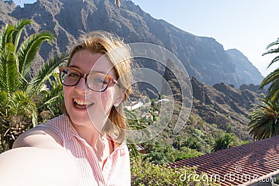 Dreamy lady with glasses smiling and taking selfie in her journey. Touristic alone woman laughing, enjoying and having fun in Stock Photo