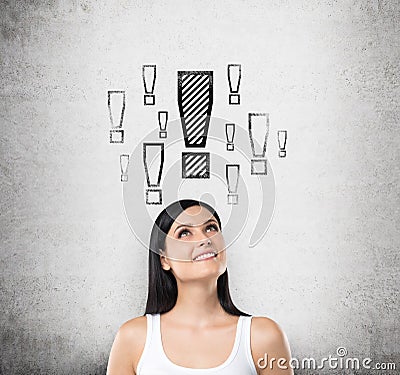 Dreamy lady is looking up. Exclamation mark are drawn above the head. Concrete background. Stock Photo