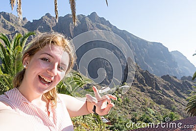 Dreamy lady making peace gesture with fingers, smiling and taking selfie in her journey. Touristic alone woman laughing, enjoying Stock Photo