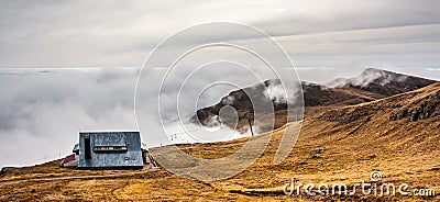 A dreamy mountain scene with a chalet and clouds cover on a mountain hill. Pastel colors sky in the background Stock Photo