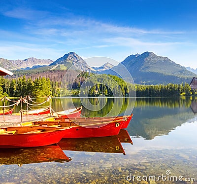 Dreamy red boats stand at the pier on a quiet lake. Stock Photo