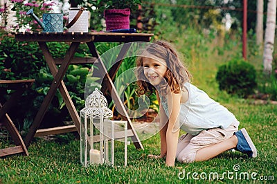 Dreamy romantic kid girl relaxing in evening summer garden decorated with lantern Stock Photo