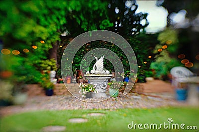 Dreamy soft focus backyard garden retreat with graceful cement swan statue Stock Photo