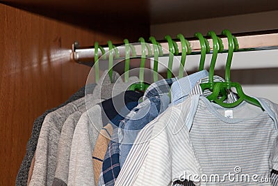 Dressing closet with complementary clothes arranged on hangers.Colorful wardrobe of newborn,kids, babies full of all clothes, shoe Stock Photo