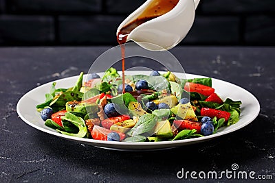 Dressing is pouring over fresh spinach salad Stock Photo