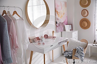 Dressing room interior with stylish makeup table, clothes and accessories Stock Photo