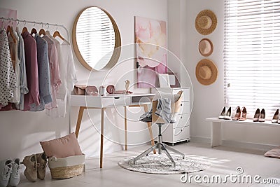 Dressing room interior with stylish makeup table, clothes and accessories Stock Photo