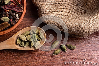Dried cardamom pods in spoon on wood background, indian spice for cooking Stock Photo