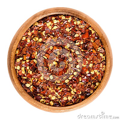 Dried chili pepper flakes in wooden bowl over white Stock Photo