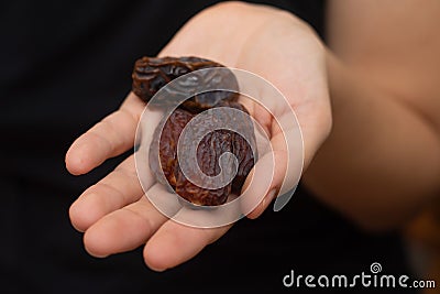 Dried Dates in Female Hand. Offering a handful of glossy, sweet dried dates Stock Photo