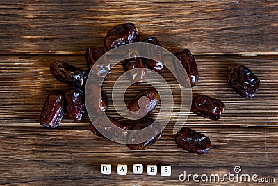 Dried dates lie on a wooden table. Explanatory inscription. View from above. Stock Photo