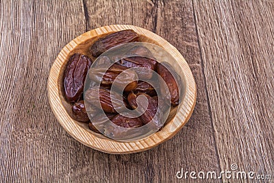 Dried dates in a wooden bowl on a wooden background Stock Photo