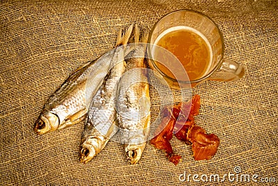 Dried fish, dried caviar and a beer mug on a homespun cloth with a rough texture. Close up Stock Photo