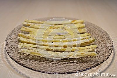 Dried fish straws on a plate on the table. Stock Photo