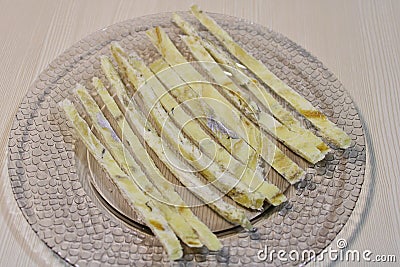 Dried fish straws on a plate on the table. Stock Photo