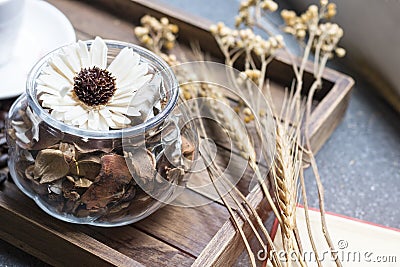 Dried flowers jar on wooden tray with warm morning light Stock Photo