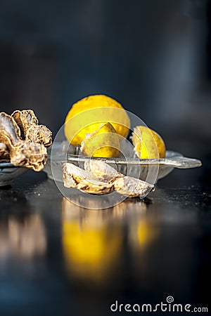Dried ginger with lemon and its juice with squeezer on wooden surface. Stock Photo