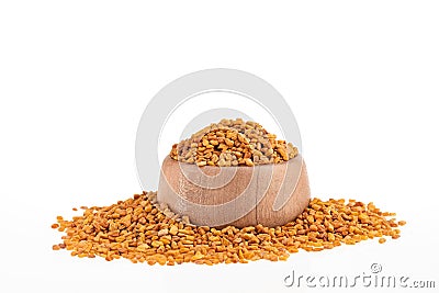 Dried organic fenugreek seeds in the wooden bowl - Trigonella foenum - graecum Stock Photo