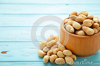 Dried peanuts in wooden bowl on blue wooden background Stock Photo