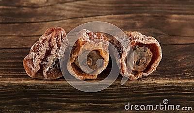 Dried Persimmon Hoshigaki. Textured wrinkled fruits on a wooden background. Useful sweets Stock Photo