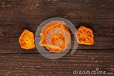 Dried persimmons. Bright orange slices on a brown wooden background. Useful sweets. Ingredients for fruit tea or punch. Selective Stock Photo