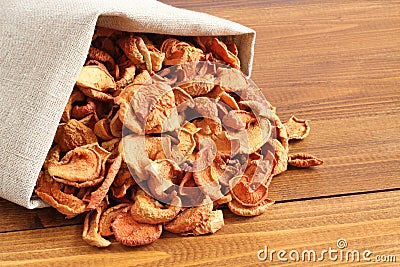 Dried pieces of apples in rough linen fabric lying on a wooden table. Coseup. Day light Stock Photo