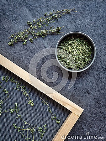 Dried thyme in metal bowl and spread on sieve in wooden frame. Overhead shot Stock Photo