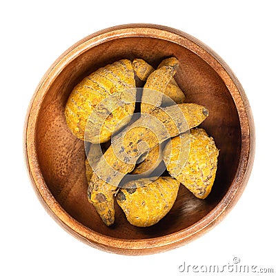 Dried whole turmeric root, dehydrated rhizomes in a wooden bowl Stock Photo