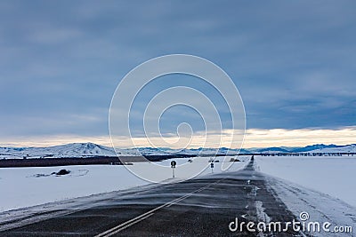 Drifting snow sweeps the road to the mountains in a gloomy sky, Altai, Russia Stock Photo