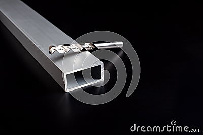 Drills from an electric drill lie on a aluminum steel tube on dark surface Stock Photo