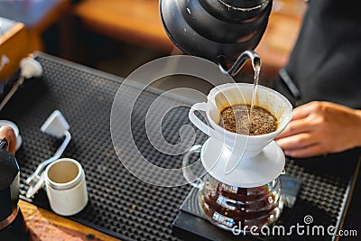 Drink coffee pot is hot, morning cafe,A hand pouring steaming coffee in to a cup on a work desk when work from home Stock Photo