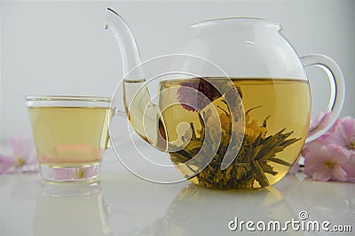 Drink of flowering tea in glass teapot with poured cup in background Stock Photo