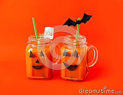 Drink for Halloween. hildren`s and party of Halloween treats. Pumpkin orange cocktail in glasses, decorated with creepy faces Stock Photo