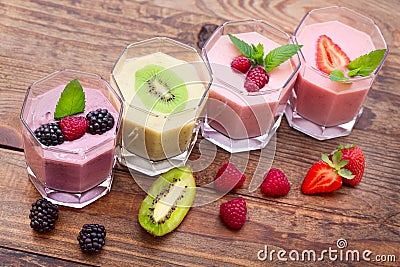 Drink smoothies four summer strawberry, blackberry, kiwi, raspberry on wooden table. Stock Photo