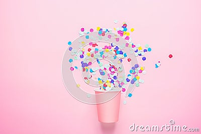 Drinking Paper Cup with Multicolored Confetti Scattered on Fuchsia Background. Flat Lay Composition. Birthday Party Celebration Stock Photo