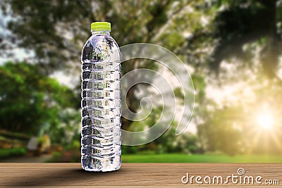 Drinking water bottle with soft shadow on wooden tabletop on blurred park with soft sunlight background Stock Photo