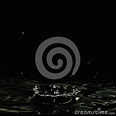 Dripping liquid, formed a dark crater and water splashes. Stock Photo