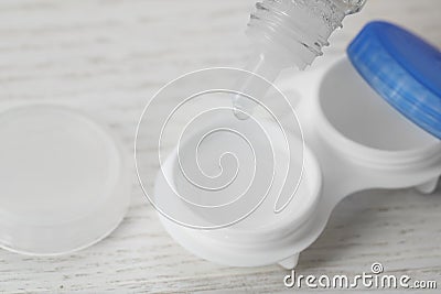 Dripping solution into case with contact lenses on white wooden table, closeup Stock Photo