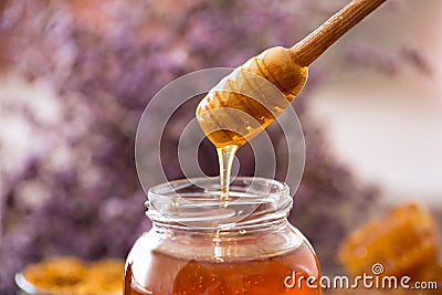 Dripping sweet golden honey from wooden dipper Stock Photo