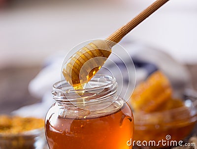 Dripping sweet honey from wooden dipper Stock Photo