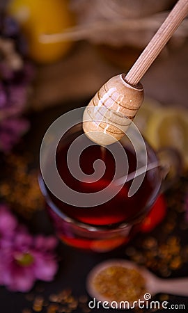 Dripping sweet honey from wooden dipper on cup of tea close-up Stock Photo