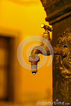 Dripping water from an old tap in the public potable fountain on a blurred background Stock Photo