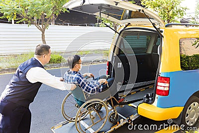 Driver helping man on wheelchair getting into taxi Stock Photo